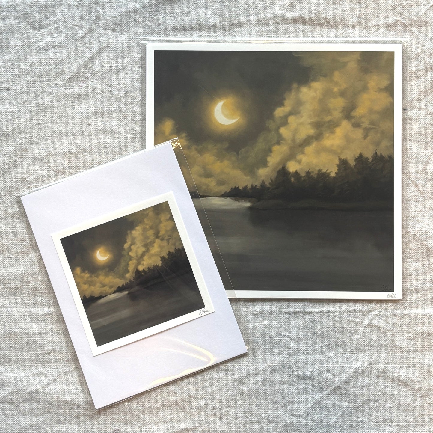 Two artworks of a moonlit landscape on textured gray fabric.
