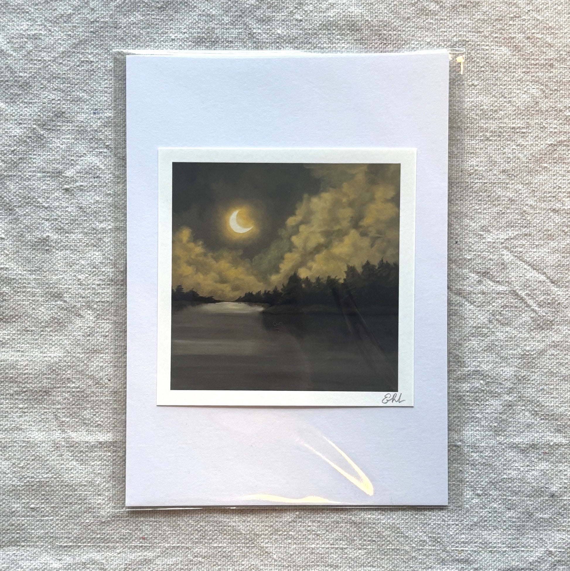Small print of a crescent moon over a landscape on textured paper.