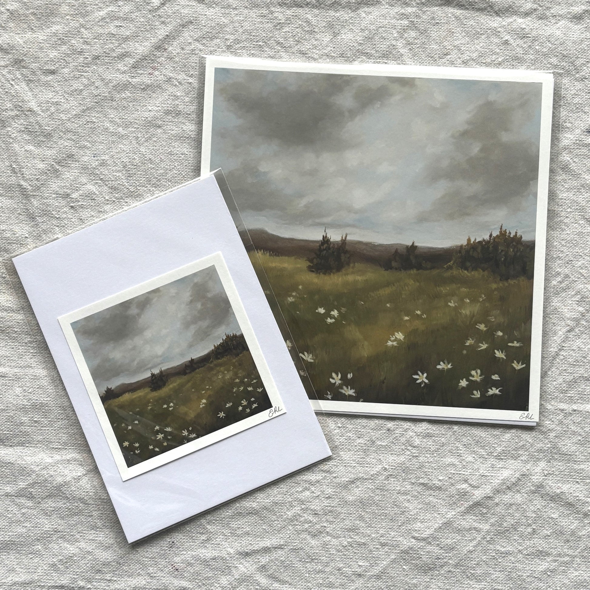 Two landscape prints on a textured gray surface