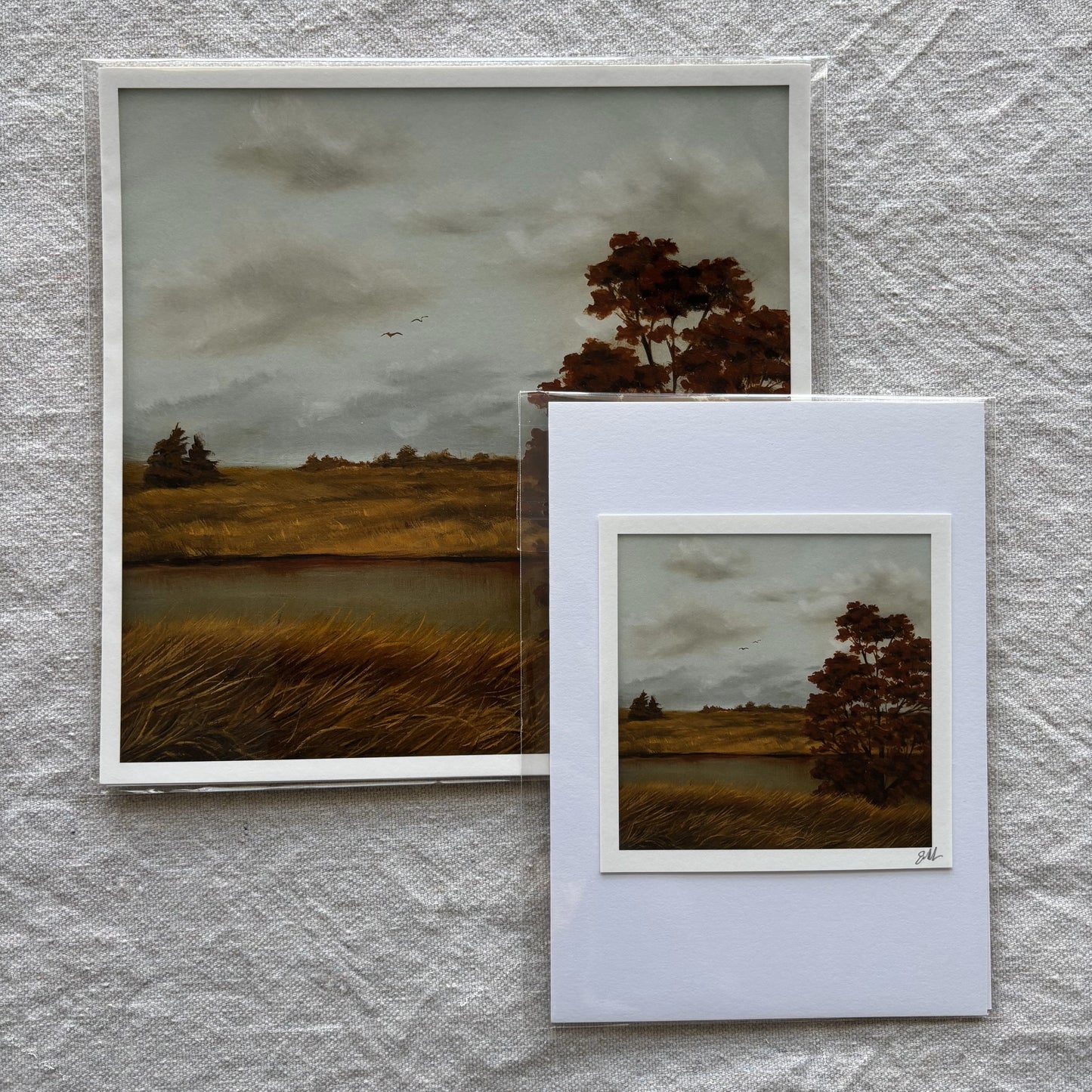 Two art prints of a landscape scene on a textured gray wall.