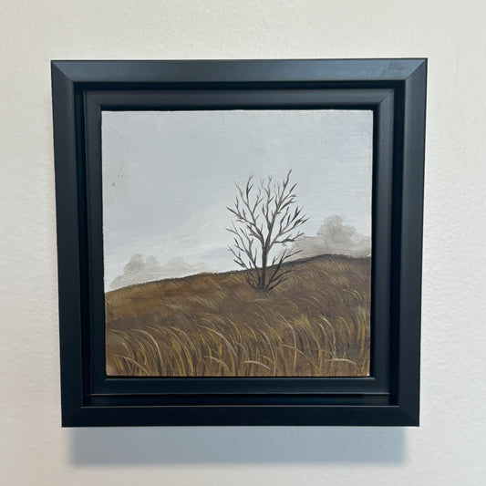 Framed artwork of a tree on a hillside with a black frame.