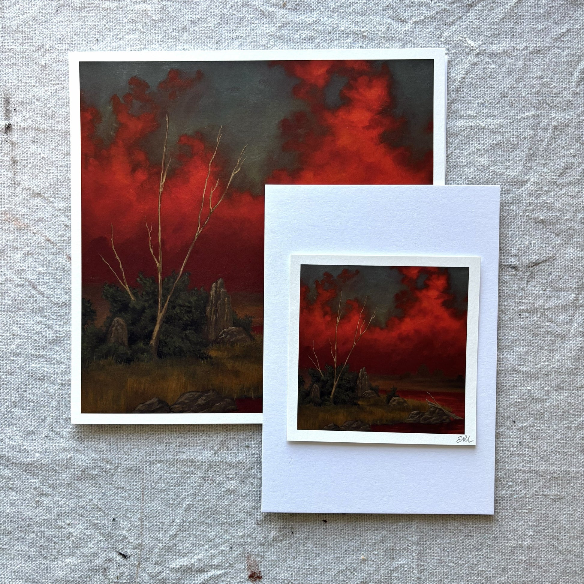 Two art prints with a fiery landscape theme on a textured gray surface.