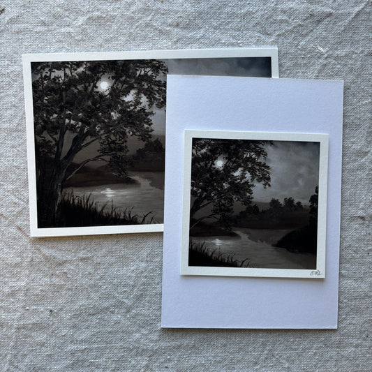 Two black and white landscape prints on a textured gray surface